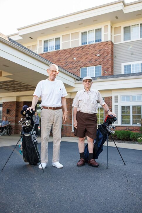 Two men standing in front of the entrance with their golf clubs