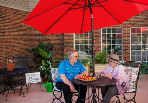 Two people sitting in the courtyard with a tray of tomatoes they picked from the raised garden.