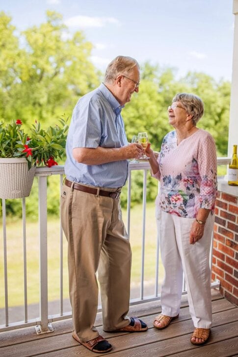 A couple toasting with wine, standing on the balcony