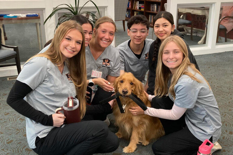 6 CNAs with a service dog at senior living