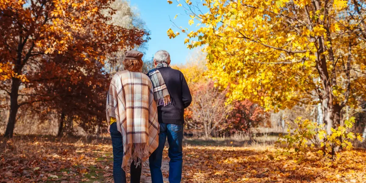 Senior couple walking through autumn park