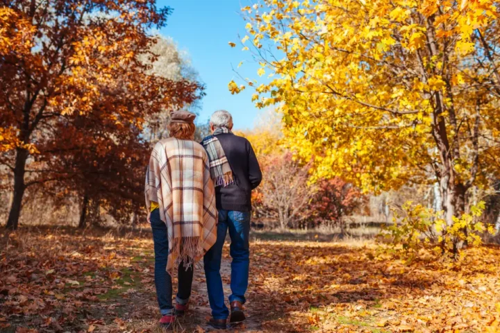 Senior couple walking through autumn park